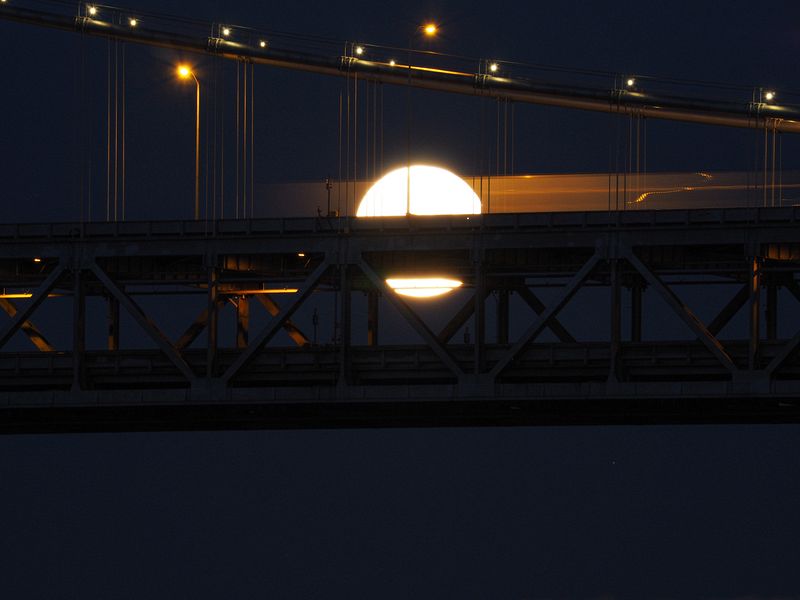 A truck drives past the moon on the Bay Bridge